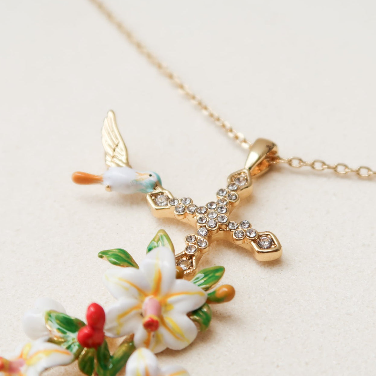 A detailed shot of Abellé’s crystal-studded floral cross necklace, Rise.