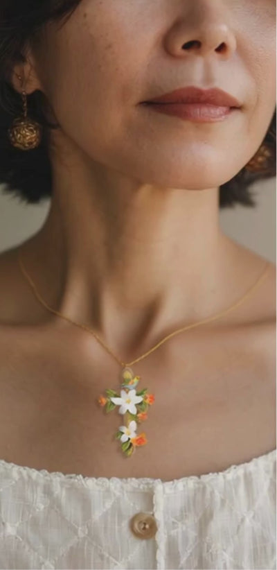 A model wearing an Abellé hand-painted floral cross necklace.